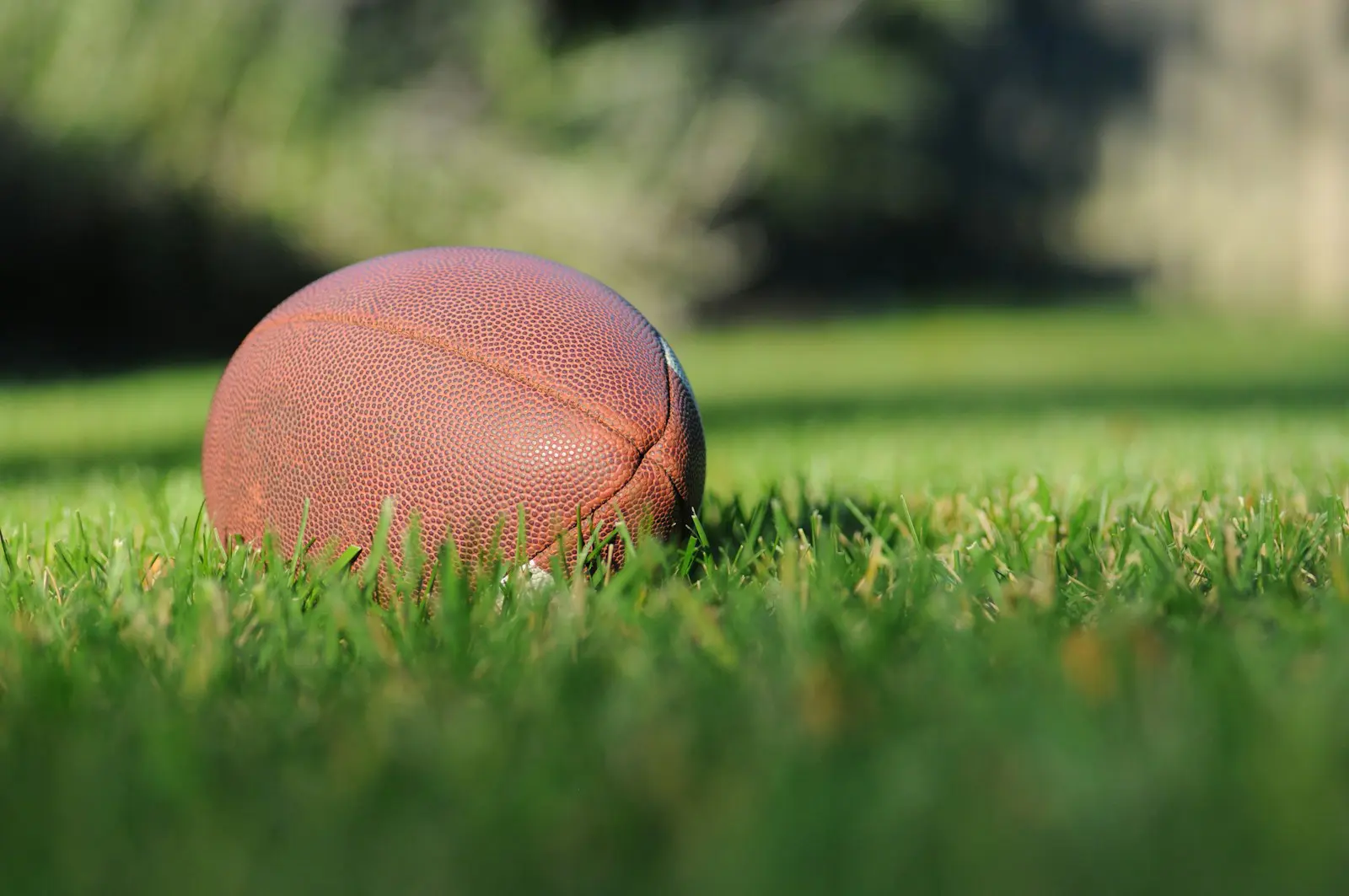 Photo by Ben Hershey selective focus photography of brown football on grass at daytime